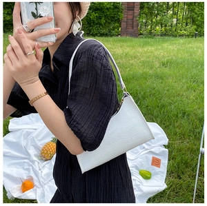 Outdoor close-up of white crocodile pattern underarm bag with elegant leather texture