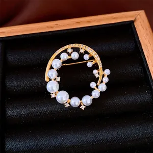 Elegant 24k gold-plated circular pearl brooch with sparkling crystals on black display