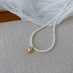Detail of s925 silver necklace with white freshwater pearls and gold hammer texture pendant