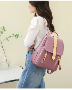 Detail view of pink oxford backpack with yellow strap and gold zippers on the flap