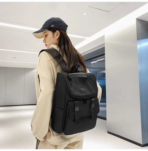 Side view of a black minimalist large capacity backpack on a model in a casual setting