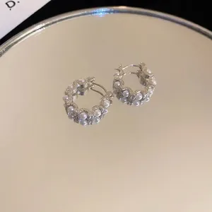French style pearl hoop earrings with silver circular base on a reflective mirror