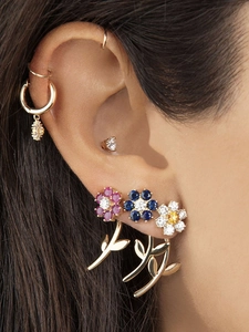 Close-up of colorful flower stud earrings with gold leaf drop jackets on female ear
