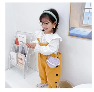 Girl model wearing purple heart-shaped quilted bag with pearl handle and chain strap