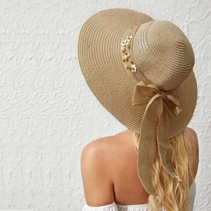 Close-up of khaki straw sun hat featuring elegant white flowers and pearl embellishments