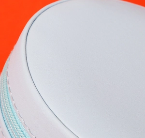 Macro detail of light blue leather jewelry box showing fine stitching and metal zipper