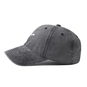 Detail of white ant embroidery on washed dark gray cotton baseball cap with vintage texture