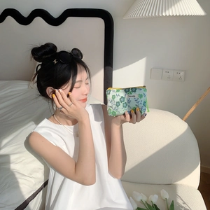 Floral makeup pouch in light green canvas held by a woman in a minimalist room