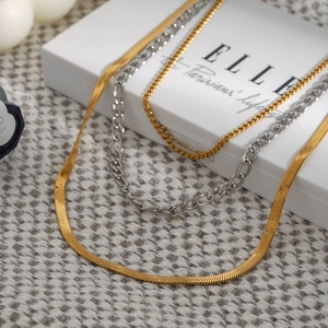Detailed view of layered gold and silver stainless steel snake and Cuban chain necklaces