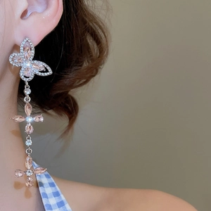 Detail shot of long tassel butterfly earrings with pink crystal inlays on model