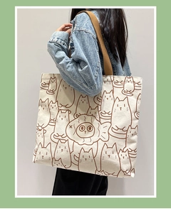 Detail of beige canvas tote bag with brown cartoon cat prints and thick fabric texture