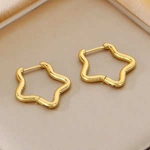 Detailed macro view of gold-plated pentagram star geometric earrings on satin background