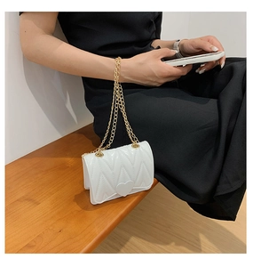 Mini white heart quilted crossbody bag with golden chain strap shown in lifestyle setting