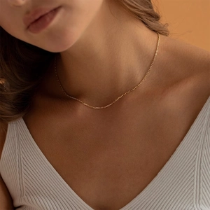 Close-up of minimalist golden punk style Cuban link chain on a model neckline