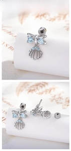 Detailed tile display of silver bow and shell cartilage stud earrings with blue zircons