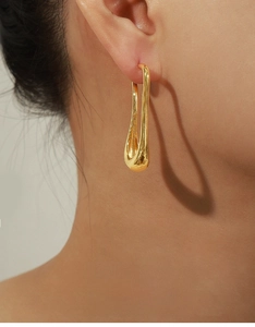 Close-up of sleek gold-plated U-shaped earrings on model highlighting minimalist design