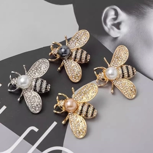 Elegant bee brooches with pearls and rhinestones shown on a stylish black backdrop