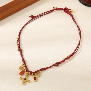 Detail of red beaded necklace with golden cross, star pendants and tiger eye stone