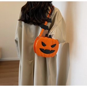Detail view of pumpkin crossbody bag with bat charms on model in trench coat