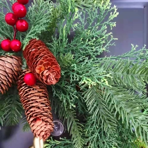 Close-up detail of farmhouse Christmas wreath with natural pine cones and red berries.