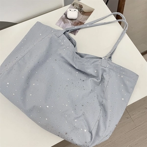 Detailed close-up of large canvas tote bag with metallic silver star prints and shoulder straps