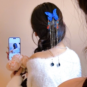 Détail de la pince à cheveux papillon bleu foncé avec franges dorées et roses