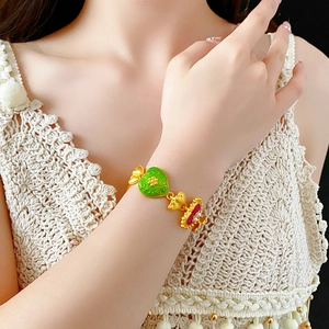 Detail of vintage gold bracelet featuring a green enamel heart and red bow charms