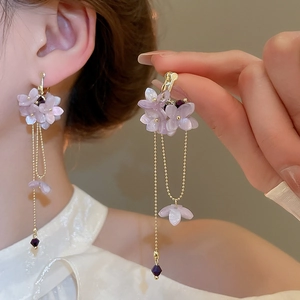 Detail of purple flower clip-on earrings with gold fringe tassels shown on ear