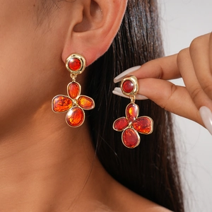 Close-up of vintage irregular gold flower earrings with deep amber resin inlay on model