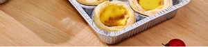 Top view of freshly baked egg tarts in a rectangular disposable silver aluminum foil tray