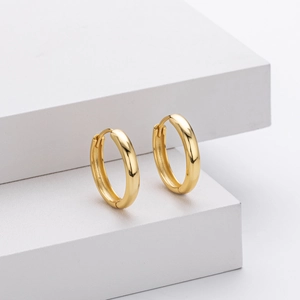 Detail of high-polished gold hoop earrings on minimalist geometric pedestals