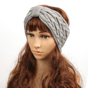 Front view of grey cable-knit winter headband with velvet lining on female model