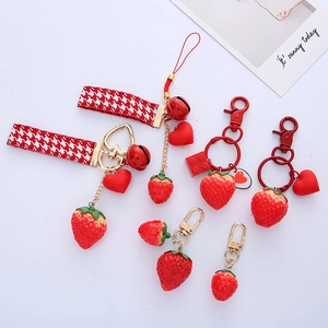 Close-up detail of cute red strawberry keychains with heart and ribbon hanging charms