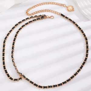Detail of elegant gold metal chain and black leather woven waist belt with coin charm