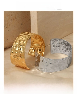 Detailed close-up of gold and silver hammered metal open bangles on a stone background