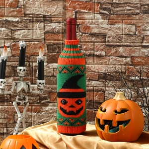 Detail of knitted Halloween wine bottle cover with pumpkin and wizard hat patterns