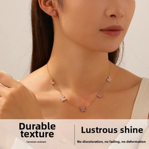 Dettaglio del set collana e orecchini con farfalle sfumate rosa viola indossato