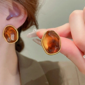 Detail showing amber resin U-shaped vintage earrings with gold-plated twisted metal edge