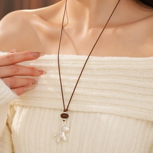 Détail du pendentif licorne argent mat sur cordon foncé porté avec un pull en maille beige
