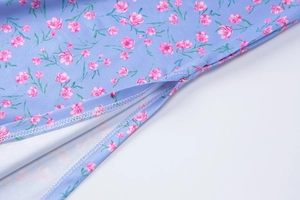 Detail of floral print fabric showing pink flowers on blue base with overlock stitching