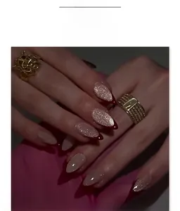 Close-up of almond-shaped champagne glitter nails with deep red French tips and cat eye finish