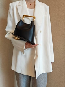 Detail of black leather bucket bag with gold metal frame handle and ball feet studs