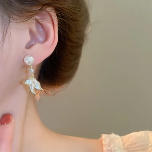 Détail d'une boucle d'oreille en perle avec pétales en émail blanc et petit accent diamant