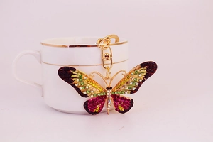 Detailed butterfly keychain with colorful crystals hanging on a white coffee cup handle