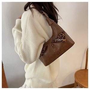 Detail of brown leather underarm bag featuring leopard print flap and fashion label