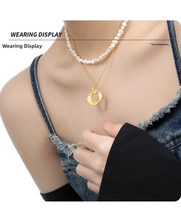 Detail of layered gold necklace with freshwater pearls and zircon pendant on a model
