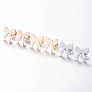 Detailed view of three pairs of stainless steel bow stud earrings in gold, silver, and rose gold