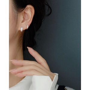 Close-up of S925 sterling silver triple-row zircon earrings worn on a model's ear