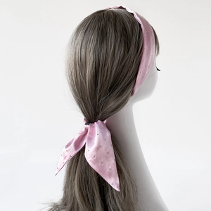 Detailansicht eines rosa Satin-Haarbandes mit silbernen Strasssteinen am Modellkopf