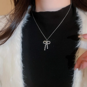 Close-up of a silver bow necklace with sparkling crystals worn on a female model